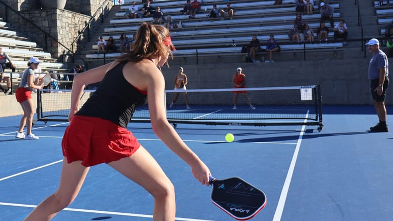 Player in orange shirt practicing pickleball stance and positioning